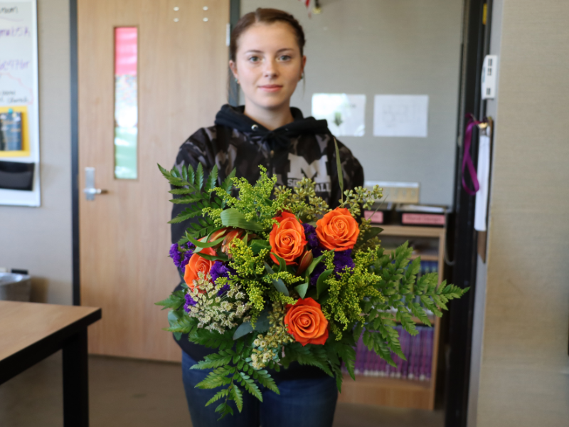 A student in floral design holds a bouquet